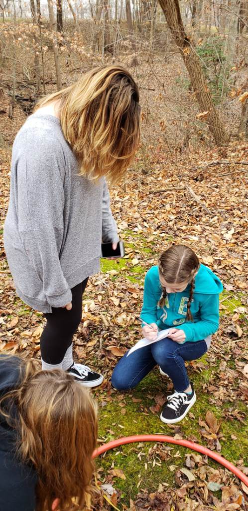 Three students writing on a sheet of paper